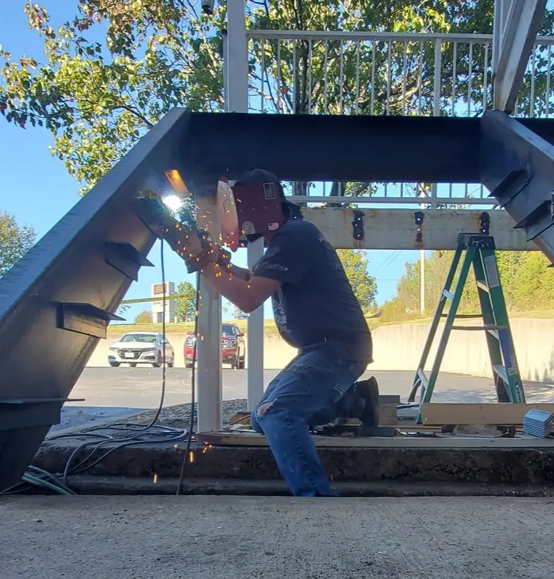 This is an image of a welder welding braces in place for an commercial outdoor staircase.