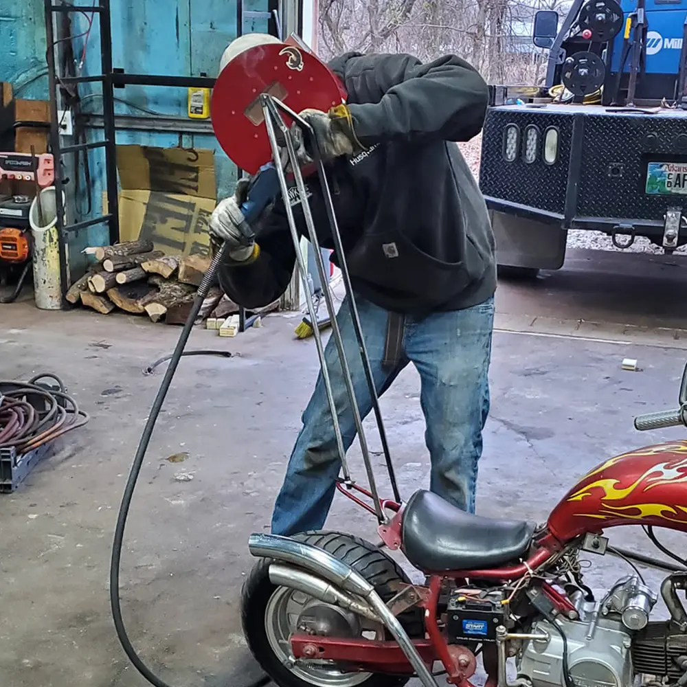 Welder repairing a motorcycle frame in the shop