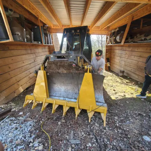 This image shows a welder repairing the front blade of heavy machinery.