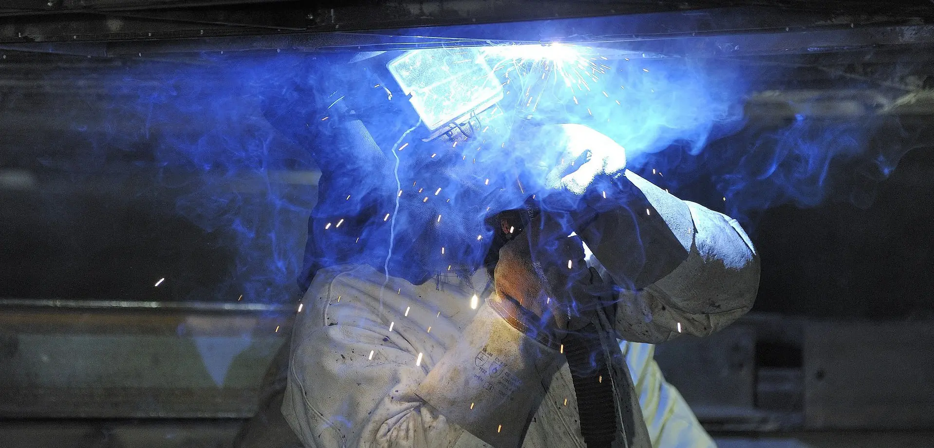 This image shows a welder welding a trailer axel for summer